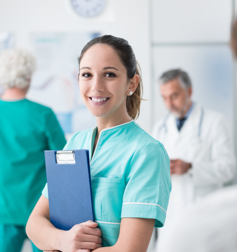 administrative assistant at physician's office holding a clipboard and smiling